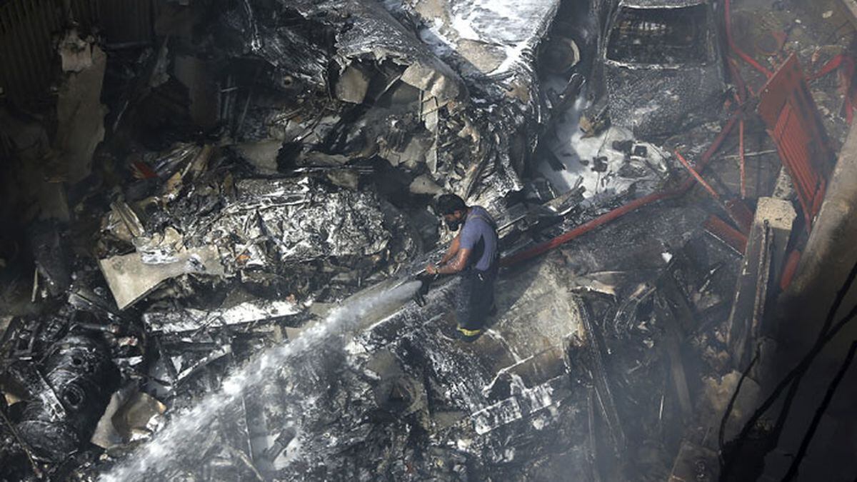 A firefighter tries to put out fire caused by plane crash in Karachi, Pakistan, Friday, May 22, 2020. An aviation official says a passenger plane belonging to state-run Pakistan International Airlines carrying more than 100 passengers and crew has crashed near the southern port city of Karachi. (AP Photo/Fareed Khan)
