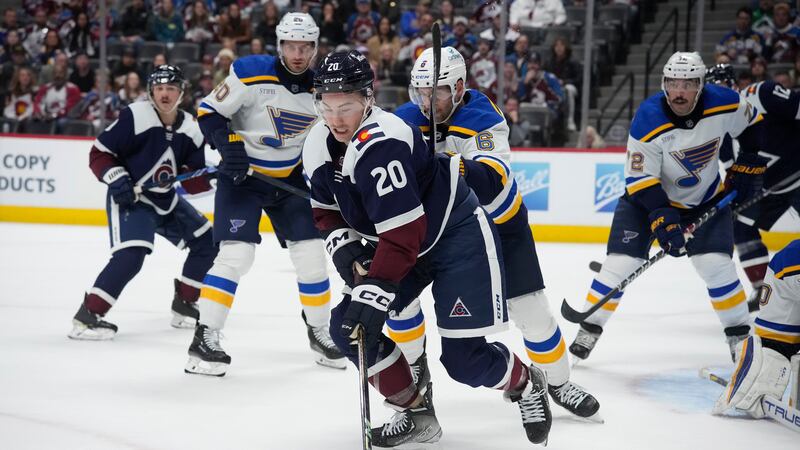 Colorado Avalanche center Ross Colton, front, passes the puck as St. Louis Blues defenseman...